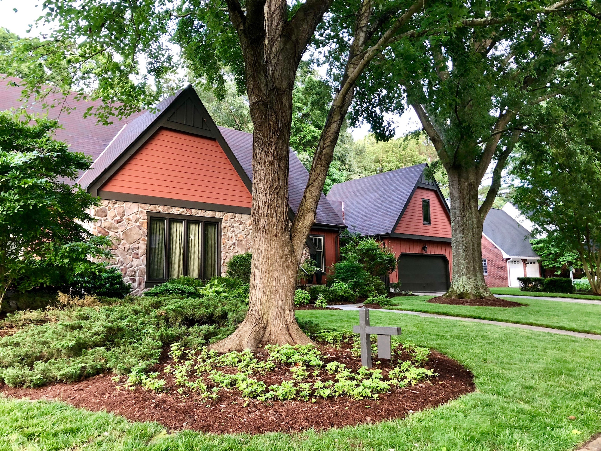 beautiful neighborhood stone facade house with well kept landscaping